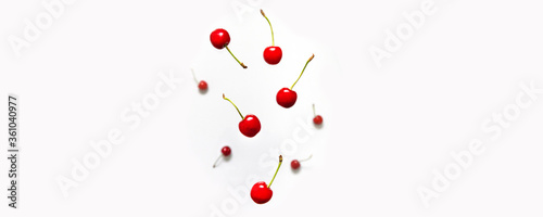 Ripe cherry berry with green leaves levitating on white background. Berry summer background. Flat lay, top view, copy space