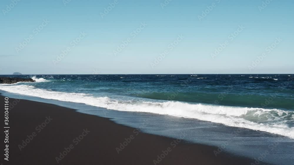 Wild beach with black volcanic sand on a sunny day. Wild beach with black volcanic sand on a sunny day.