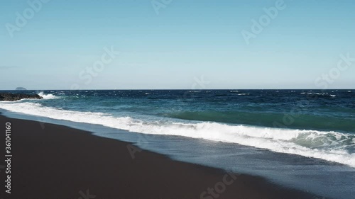 Wild beach with black volcanic sand on a sunny day.