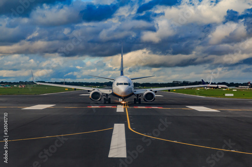 Airplane on the tarmac with runway and marking on the tarmac. Airplane rolls to takeoff. In the background clouds in the sky