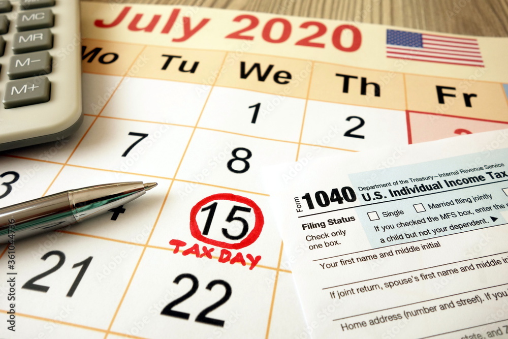 Monthly calendar showing date July 15th 2020 marked as tax day with 1040 form calculator and pen