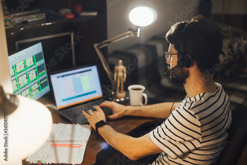 Stylish bearded man working remotely from home at night