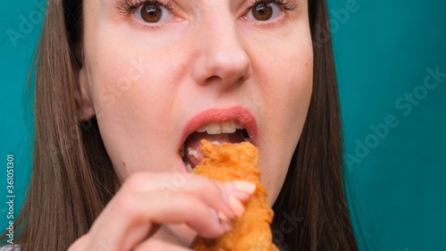 Young happy woman eating deep fried chicken  closeup. Woman eats chicken wings  calorie intake and health risks  cholesterol