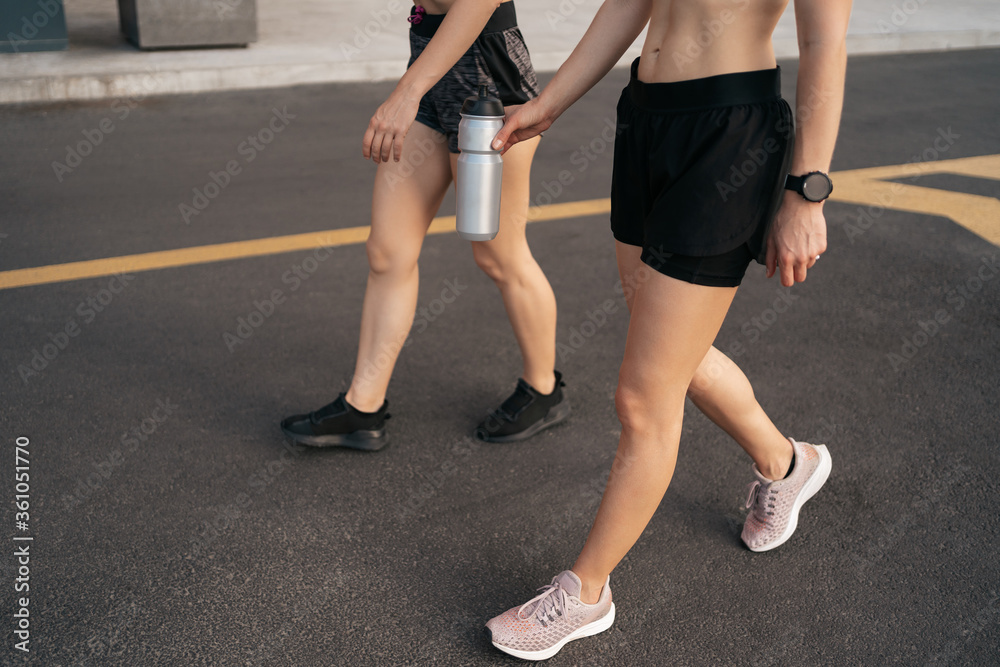 Young woman running on sidewalk in morning. Health conscious concept. Healthy active lifestyle. Active girls jogging together on road in the city. Young woman running on sidewalk in morning. Health conscious concept. Healthy active lifestyle. Active girls jogging together on road in the city.