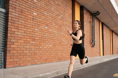 Young woman sprinting in the morning outdoors. Female runner working out in the city.