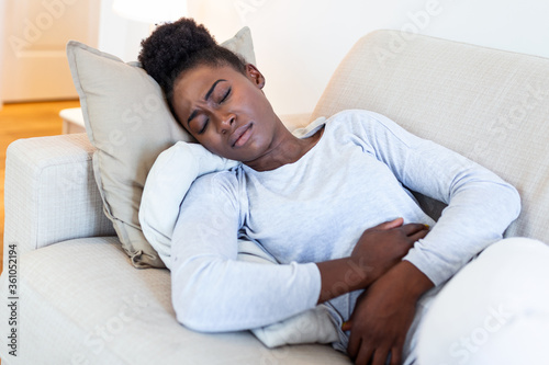 Εκτύπωση καμβά Woman in painful expression holding hands against belly suffering menstrual peri