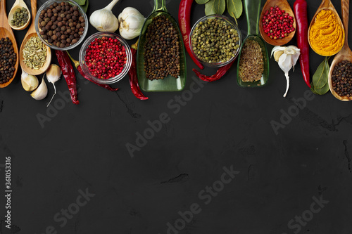 Various exotic spices in wooden spoons on dark background
