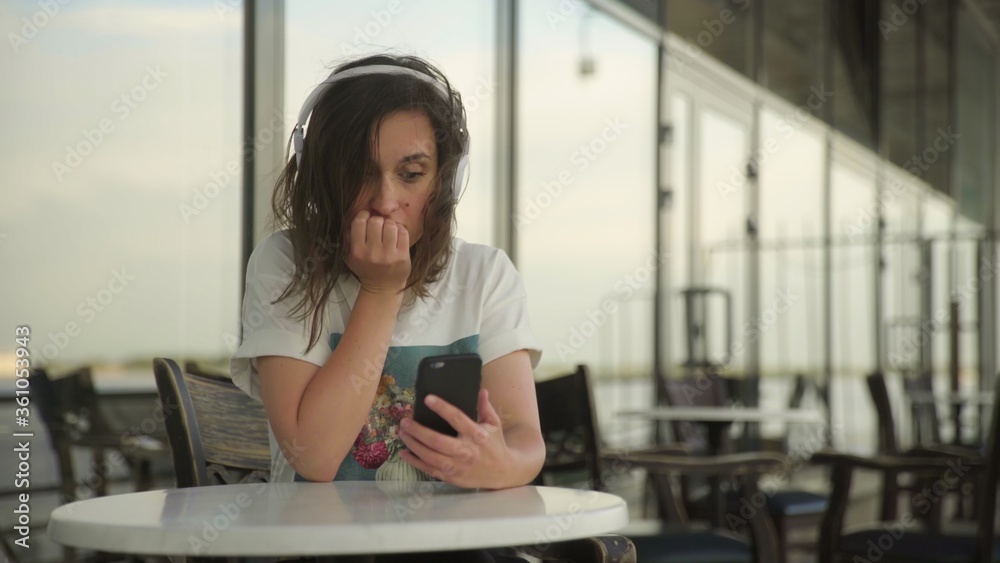 Young woman in headphones looking at the smartphone Young woman in headphones looking at the smartphone