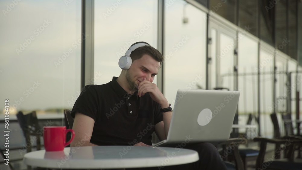 Young man watching comedy movie on laptop while sitting in cafe Young man watching comedy movie on laptop while sitting in cafe