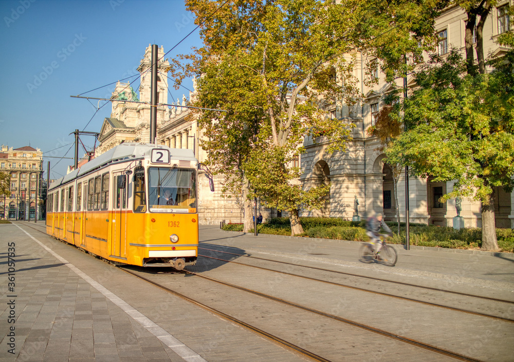 Fototapeta premium Żółty tramwaj poruszający się wzdłuż drogi miasta w Budapeszcie, Węgry.