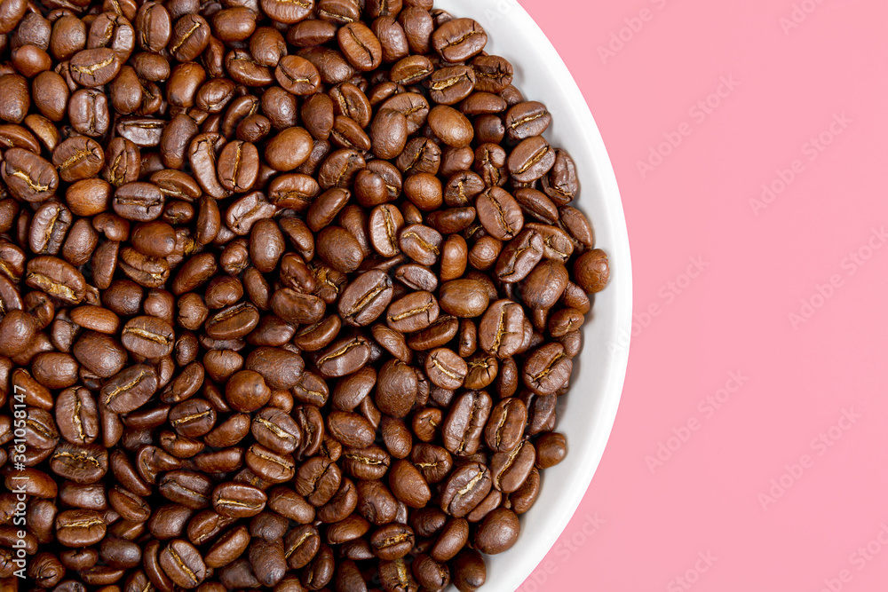 Fragrant coffee beans on a white plate on a pink background. Beautiful background and texture. Coffee shop or store concept. Top view, closeup, copy space. Fragrant coffee beans on a white plate on a pink background. Beautiful background and texture. Coffee shop or store concept. Top view, closeup, copy space.