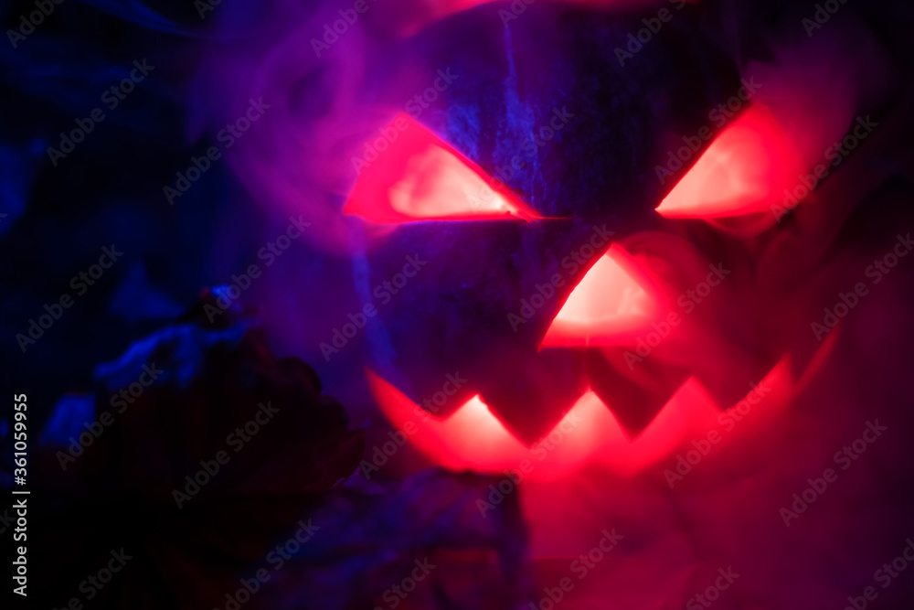 Glowing pumpkin in the dark releasing smoke from the eyes and mouth close-up. Background for Halloween. Glowing pumpkin in the dark releasing smoke from the eyes and mouth close-up. Background for Halloween.