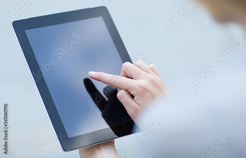 Close-up of woman's finger pressing on a digital tablet touchscreen device. Online shopping/banking concept.