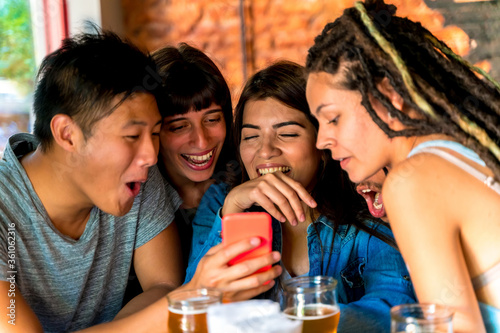 A group of friends laughing at a screen of a phone