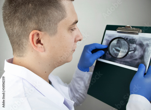 A dentist doctor examines a radiography of the teeth of a patient who has problems and teeth are inserted. The concept of research and diagnosis photo