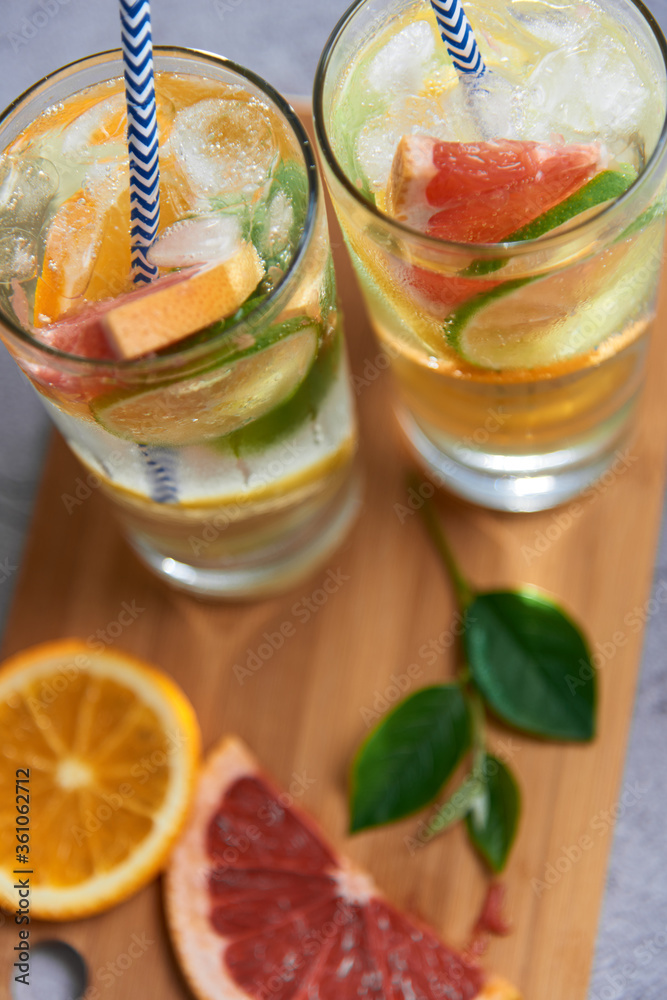 Health care, fitness, healthy nutrition diet concept. Fresh cool homemade citrus infused detox water with grapefruit, orange, lemon and lime and ice in a jug and glasses for spring summer days. Health care, fitness, healthy nutrition diet concept. Fresh cool homemade citrus infused detox water with grapefruit, orange, lemon and lime and ice in a jug and glasses for spring summer days.