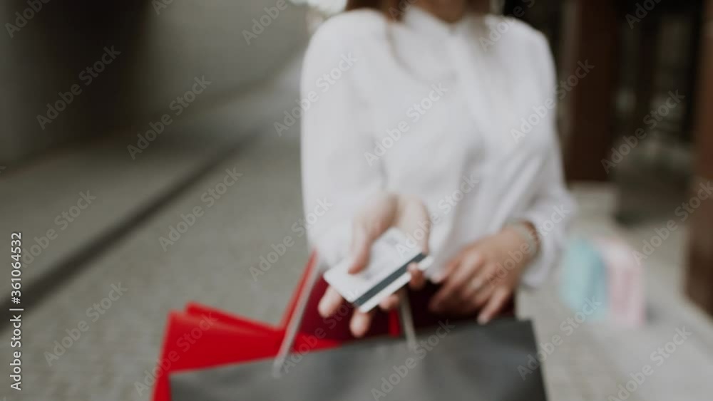 Young woman in red dress with shopping bags walks on the street during sunset Young woman in red dress with shopping bags walks on the street during sunset