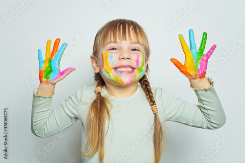 Happy girl drawing and showing her colorful painted hands on white background portrait