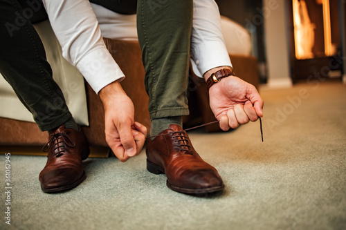 Elegant man tying shoelace at a hotel room, low angle image.