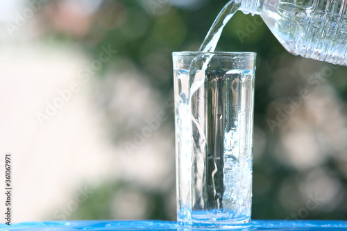 Glass of water on wood table background and pouring drinking water