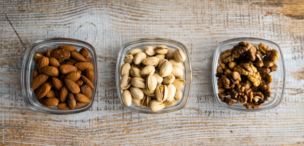 Almond, pistachio and walnut in a small plates which standing on a vintage white table. Nuts is a healthy vegetarian protein and nutritious food. Almond, pistachio and walnut in a small plates which standing on a vintage white table. Nuts is a healthy vegetarian protein and nutritious food.