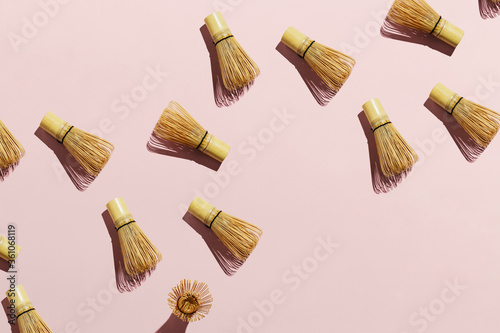 Flatlay of bamboo matcha tea whisks on pink pastel background