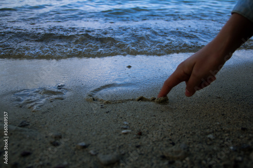 Hand drawing a heart in the sand