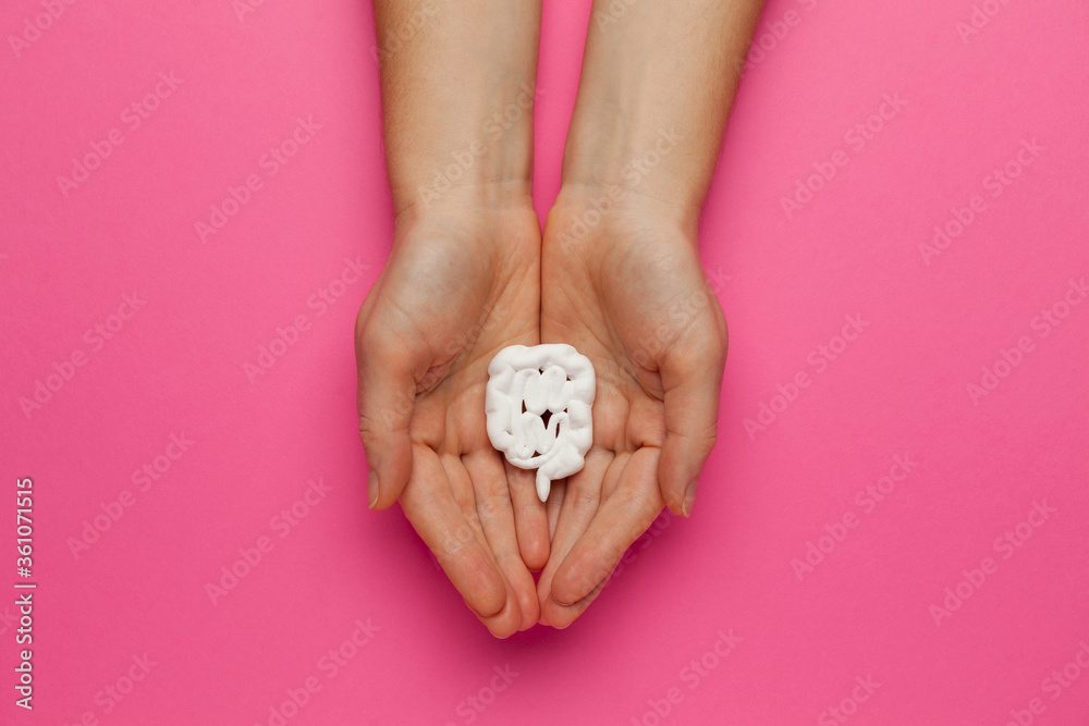 Intestines and white pills on a pink background. Gastrointestinal tract inflammation. Digestive pain, treatment of dysbiosis. probiotics Intestines and white pills on a pink background. Gastrointestinal tract inflammation. Digestive pain, treatment of dysbiosis. probiotics