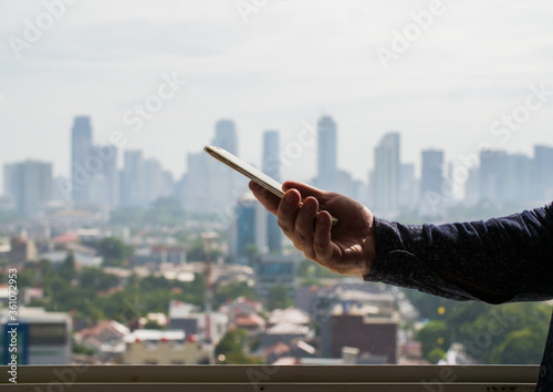 A man uses a phone against the backdrop of a panorama of a metropolis.