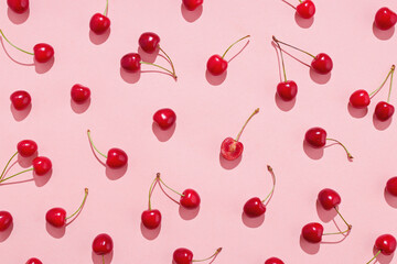 Flat lay of cherries on a pink background.