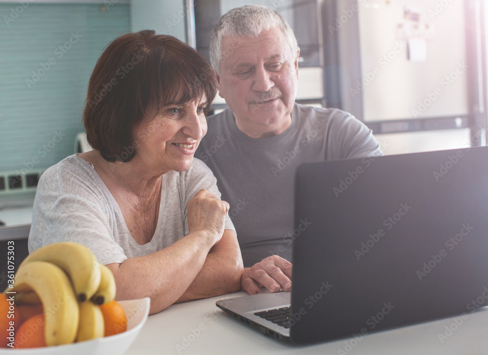 Elderly couple looking at computer in the kitchen