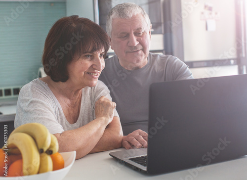 Elderly couple looking at computer in the kitchen