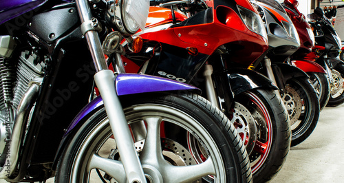 Beautiful group parking of motorcycles in a showroom for sale, in a store close-up. Maintenance of sportbikes, road bikes in the workshop. Moto parts, wheels, headlights, engine. Banner for web site © Maksim