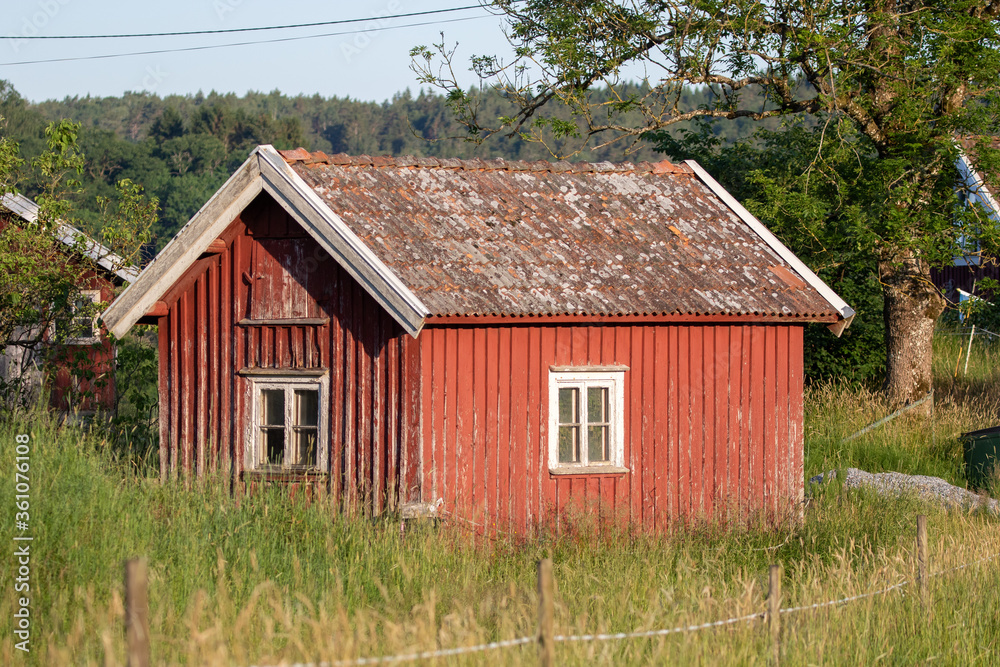 A red wooden cottage by a farm in Sweden