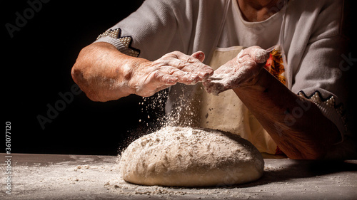 Fototapeta Naklejka Na Ścianę i Meble -  White flour flying into air as pastry, slams ball dough. Food concept. space for text