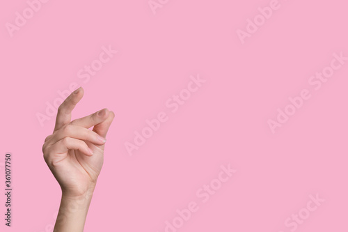 Female beautiful caucasian hand snaps fingers. pink background.