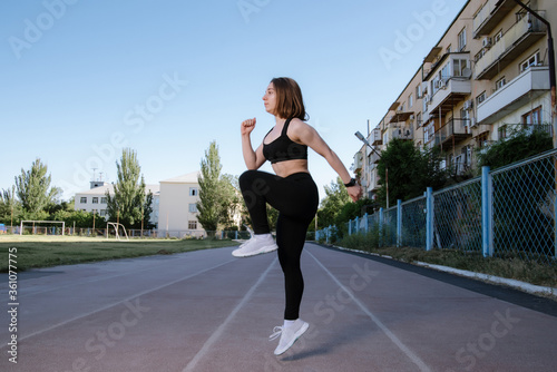 Portrait of attractive sport woman in sportswear posing outdoors at the stadium. © bo.kvk