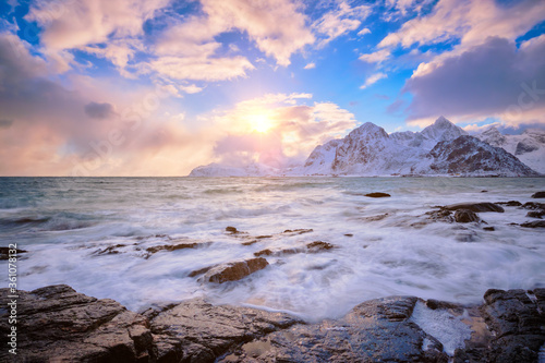 Beach of Norwegian sea on rocky coast in fjord on sunset in winter. Vareid beach, Lofoten islands, Norway