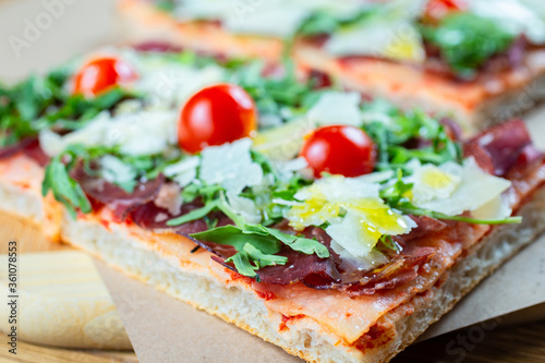 pizza with cherry tomatoes, parmesan cheese, arugula and smoked ham