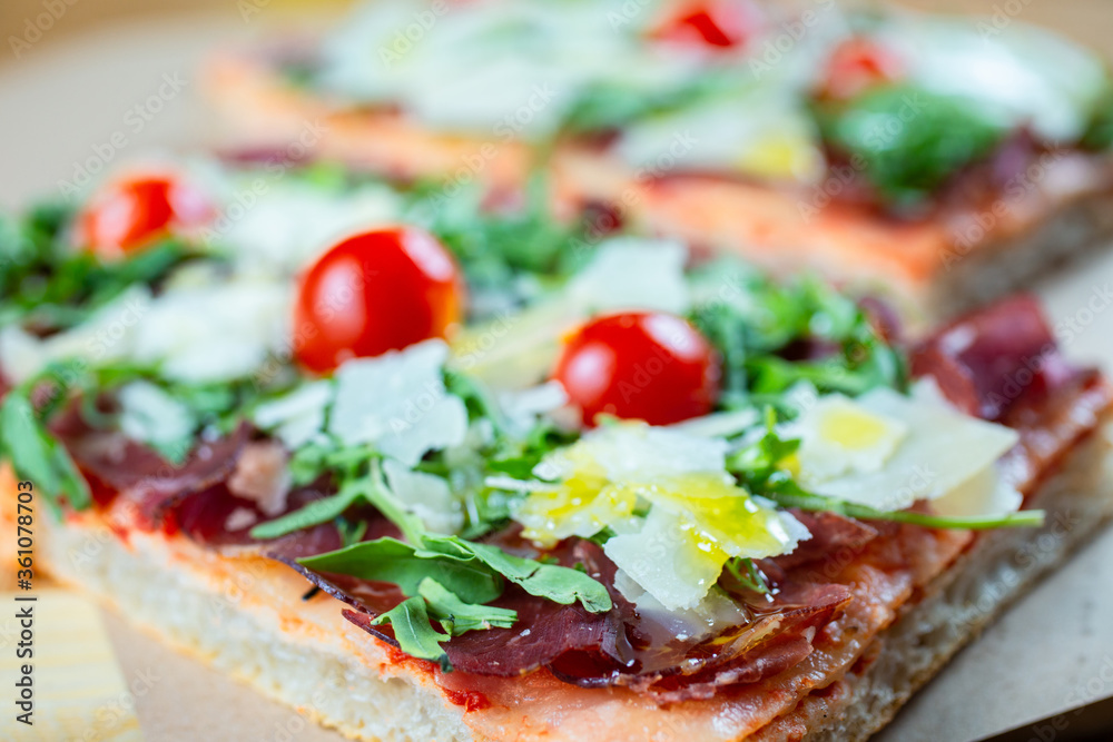pizza with cherry tomatoes, parmesan cheese, arugula and smoked ham