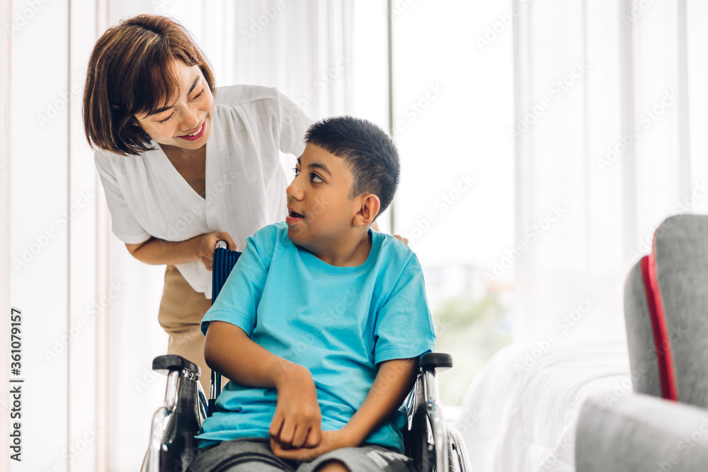 Portrait of enjoy happy love family asian mother playing and carer helping look at disabled son child sitting in wheelchair moments good time at home.disability care concept Portrait of enjoy happy love family asian mother playing and carer helping look at disabled son child sitting in wheelchair moments good time at home.disability care concept