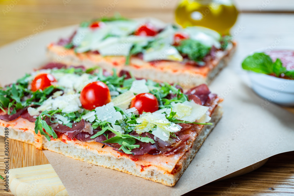 pizza with cherry tomatoes, parmesan cheese, arugula and smoked ham
