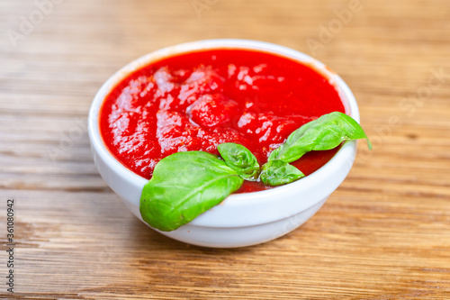 tomato sauce with fresh basil on a wooden background