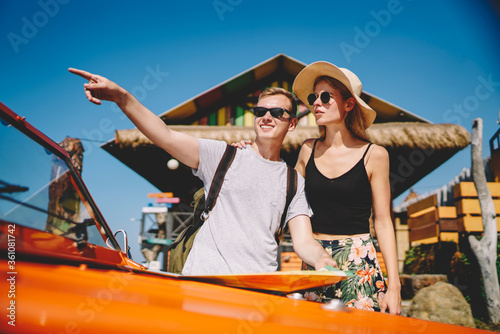 Young hipsters in eyewear stopping rental car discussing and choosing way for getting to destination,romantic couple resting during summer weekends having touristic roadtrip on tropical island © BullRun