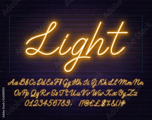 Neon yellow script font. Glowing alphabet with letters, numbers and special characters on a brick background.
