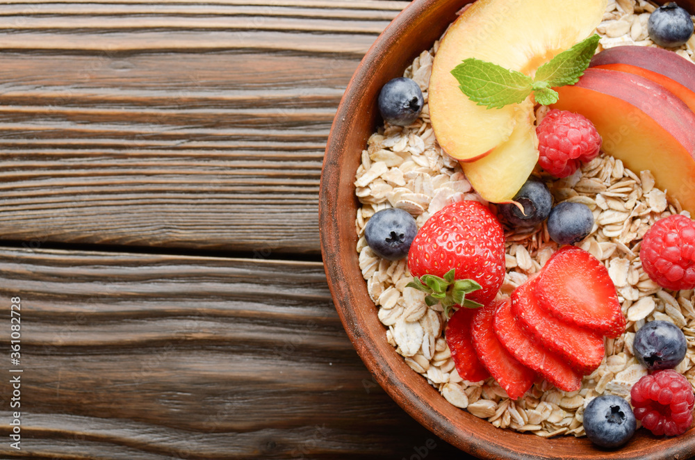 Flat lay of fruit healthy muesli with peaches strawberry almonds and blackberry in clay dish on wooden kitchen table Flat lay of fruit healthy muesli with peaches strawberry almonds and blackberry in clay dish on wooden kitchen table