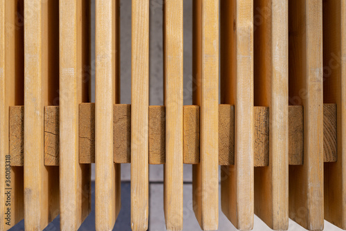 Parallel wooden planks of yellow color on a background of gray concrete