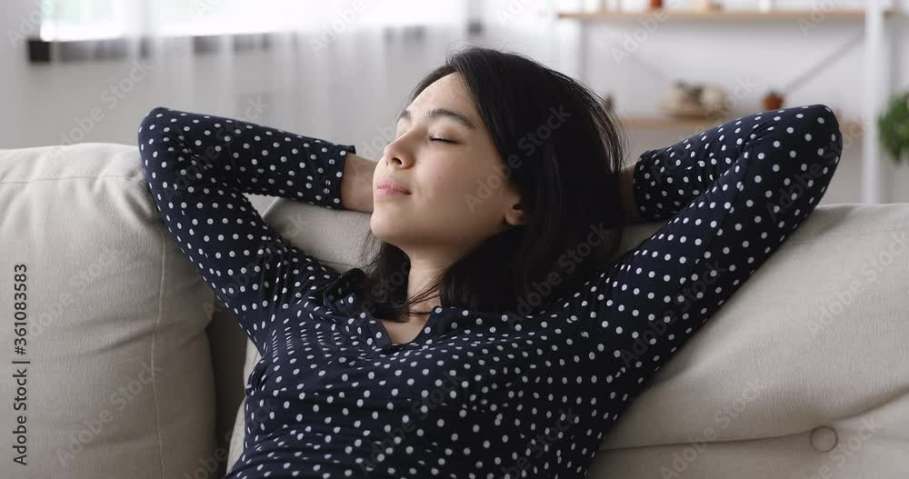 Close up Asian woman lean on couch relaxing put hands behind head open eyes looks into distance. Lazy day, admire view out the window, rented flat satisfied renter, enjoy air-conditioned air concept Close up Asian woman lean on couch relaxing put hands behind head open eyes looks into distance. Lazy day, admire view out the window, rented flat satisfied renter, enjoy air-conditioned air concept