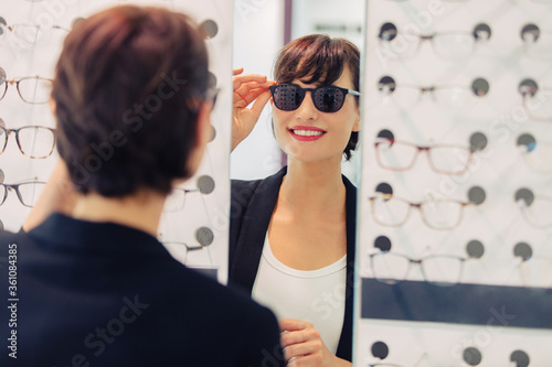 Obraz na płótnie a woman tries on sunglasses in a glasses store
