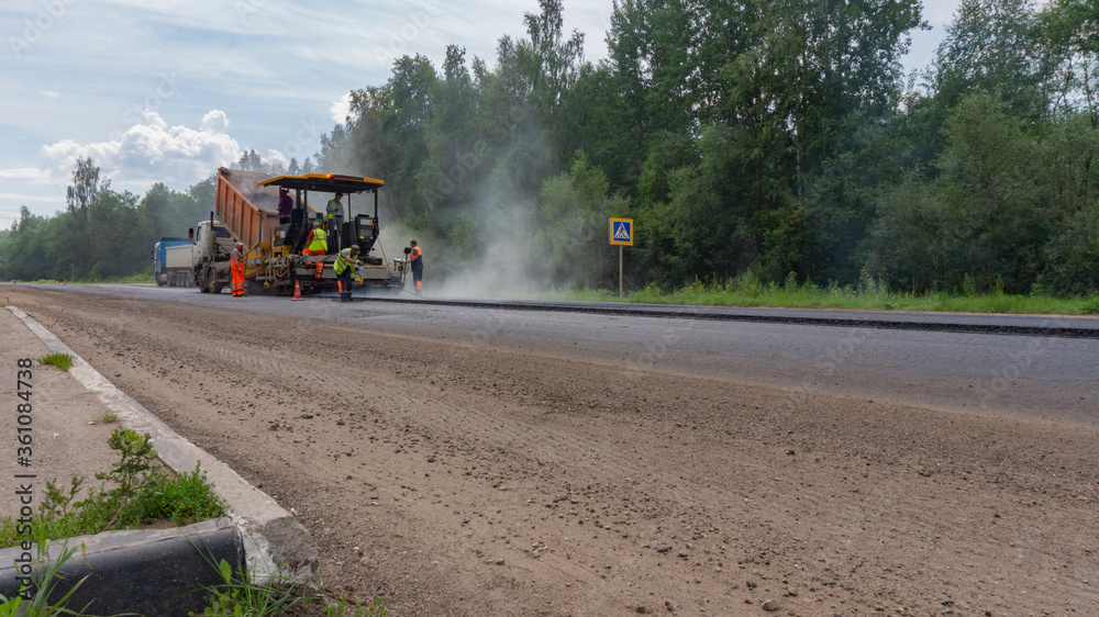 Fototapeta premium Asphalt paver machinery with workers. Road repair works on the suburb highway